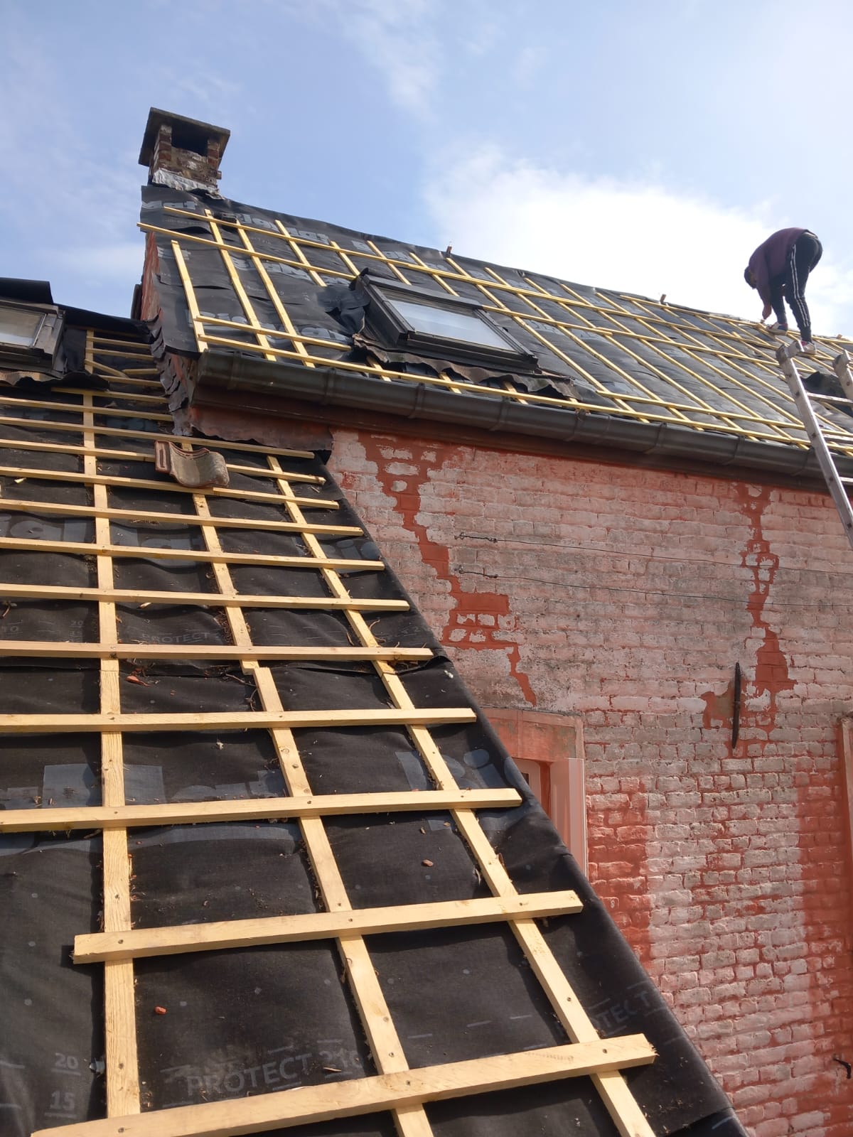 Lattage neuf terminé sur une toiture, couvreur en cours d'intervention